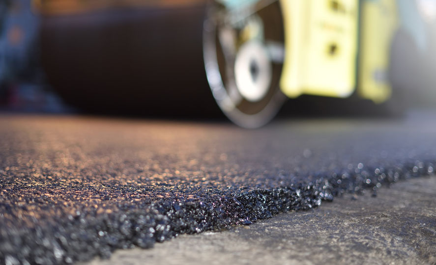 Thin layer of new asphalt close-up and road roller